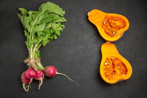 Vista superior de calabaza fresca con verduras y rábano sobre fondo oscuro