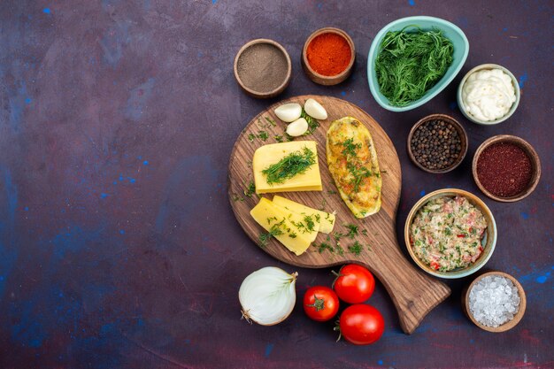 Vista superior de calabazas al horno con condimentos de verduras de queso, carne picada y verduras frescas en el escritorio oscuro.