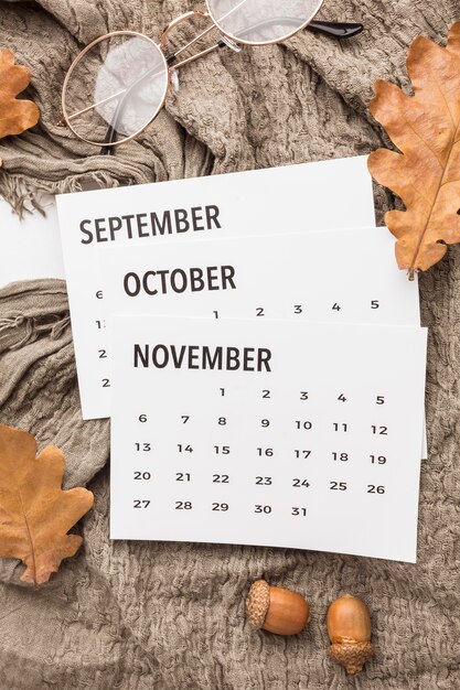 Vista superior del calendario con hojas de otoño y gafas