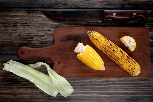 Vista superior de callos cocidos en tabla de cortar con cáscara de maíz y cuchillo en madera