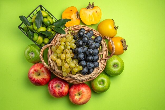 Vista superior canasta de frutas de racimos de uvas caquis manzanas canasta de frutas cítricas