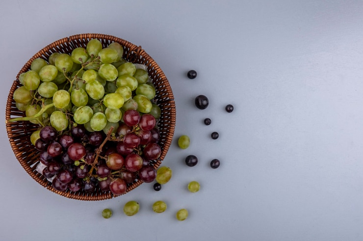 Foto gratuito vista superior de la canasta de uvas y bayas de uva sobre fondo gris con espacio de copia