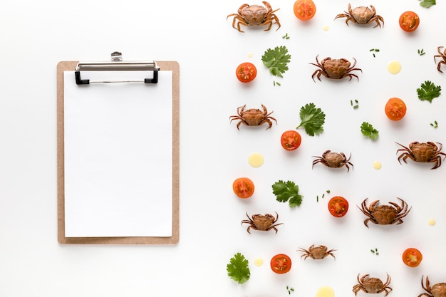 Vista superior de cangrejos y tomates con bloc de notas