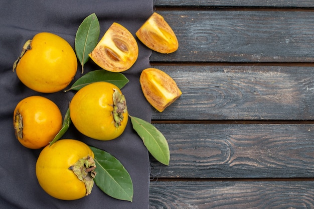 Vista superior caquis dulces frescos en una mesa rústica de madera, fruta suave