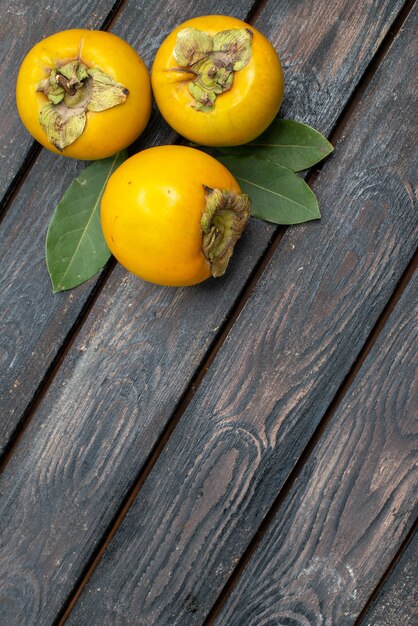 Vista superior de los caquis dulces frescos en la mesa rústica de madera, frutas maduras suaves
