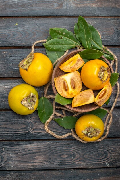 Vista superior de los caquis dulces frescos en la mesa rústica de madera, pruebe la fruta madura