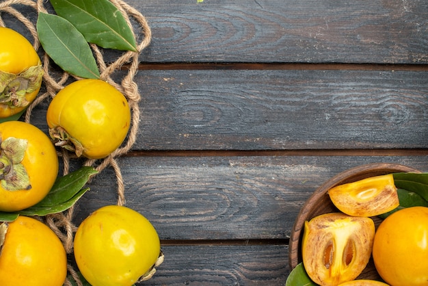 Vista superior de los caquis dulces frescos en la mesa rústica de madera, sabor a fruta madura