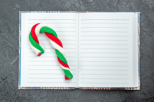 Foto gratuita vista superior de un caramelo de navidad en el cuaderno abierto sobre fondo oscuro