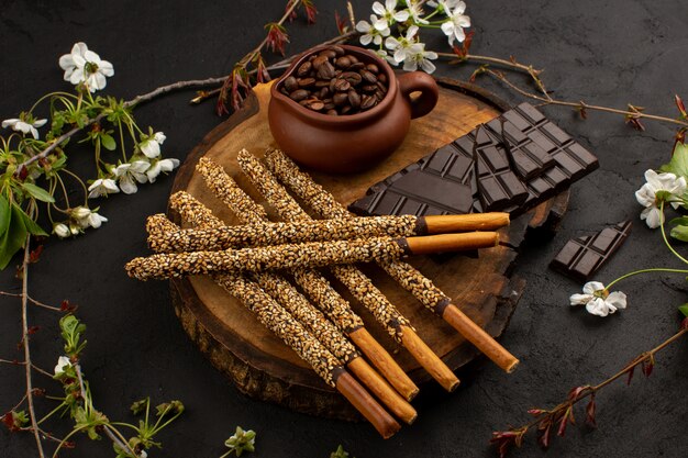 Vista superior de caramelo pega chocolate junto con semillas de café en el escritorio marrón y oscuro