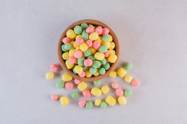 Vista superior de caramelos de colores caseros en un tazón sobre gris.