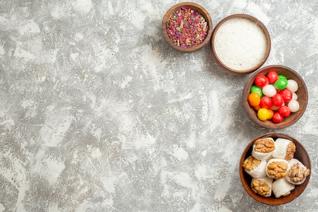 Vista superior de caramelos de colores con confituras de nueces en el arco iris de caramelo de color blanco de mesa