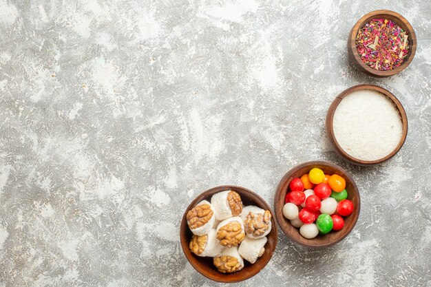 Vista superior de caramelos de colores con confituras de nueces en la mesa blanca, color arco iris, dulces frutos secos