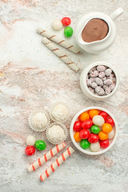 Vista superior de caramelos de colores con galletas en el pastel de té de la galleta del arco iris del color del escritorio blanco