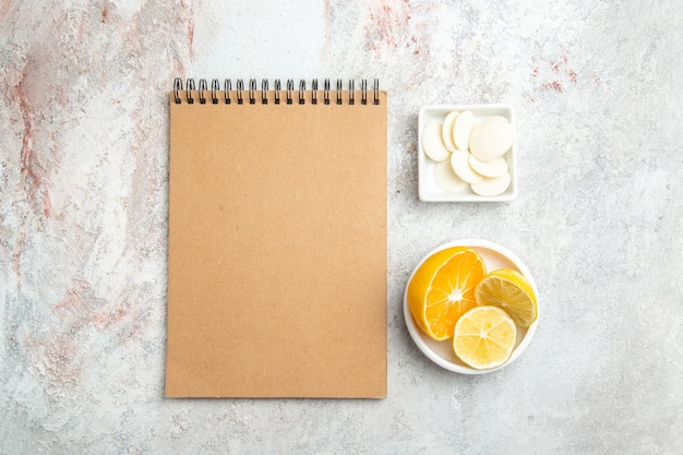Vista superior de caramelos dulces con limón y bloc de notas en mesa blanca fruta de galleta de caramelo