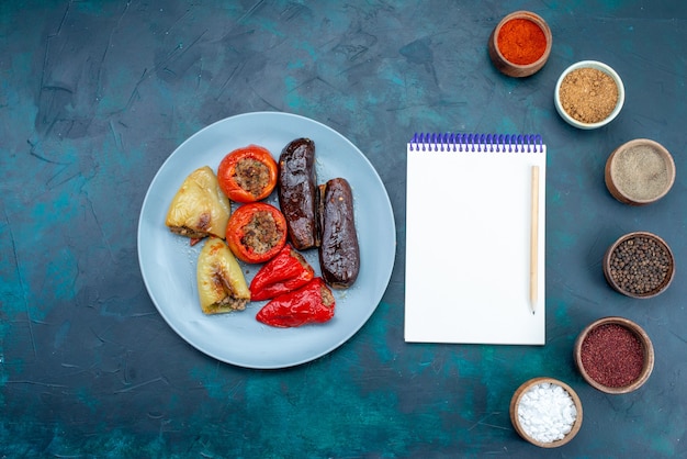 Foto gratuita vista superior de la carne dentro de las verduras dolma junto con los condimentos y un pequeño bloc de notas en el escritorio oscuro, comida, carne, cena, salud, engorde