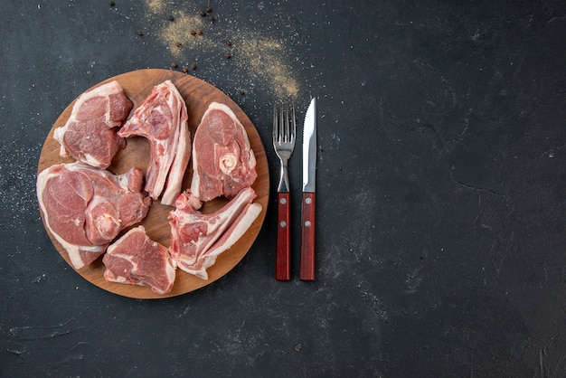 Vista superior de la carne fresca rebanadas de carne cruda con un tenedor y un cuchillo en la cocina oscura comida de ensalada comida comida de vaca plato de animales
