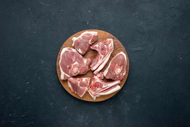 Vista superior de la carne fresca en rodajas de carne cruda en el escritorio de madera redonda en la frescura de los alimentos oscuros comida de la vaca animal comida cocina