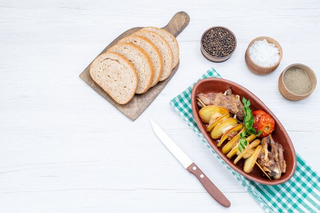 Vista superior de la carne frita con verduras y ciruelas al horno dentro de la placa con panes de pan sal en la mesa de luz, comida, comida, plato de carne, cena