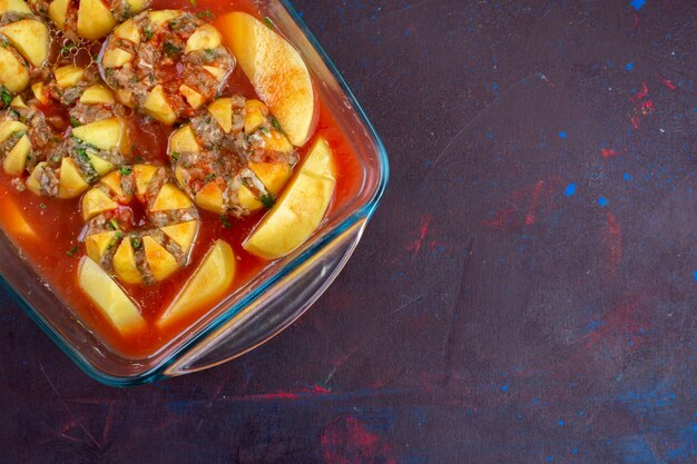 Foto gratuita vista superior de la carne picada dentro de las patatas en la superficie de color púrpura oscuro