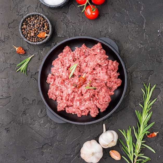 Vista superior de carne en plato con tomates y hierbas