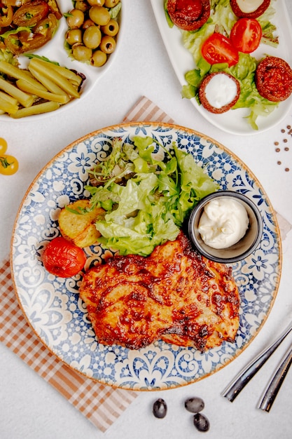 Vista superior de carne de pollo al horno con queso patatas asadas y tomates