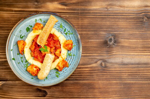 Vista superior de la carne en salsa con puré de patatas y pan en rodajas en la mesa de madera marrón. carne pan papa comida