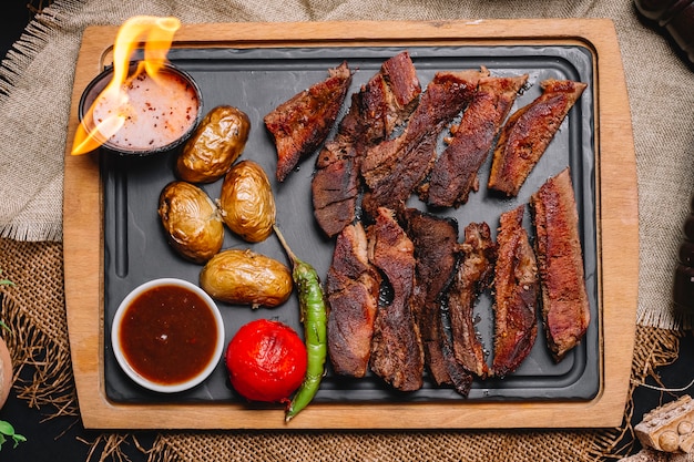 Vista superior de carnes a la brasa con patatas y verduras a la plancha con salsas