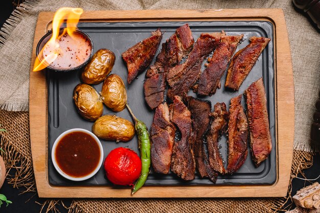 Vista superior de carnes a la brasa con patatas y verduras a la plancha con salsas