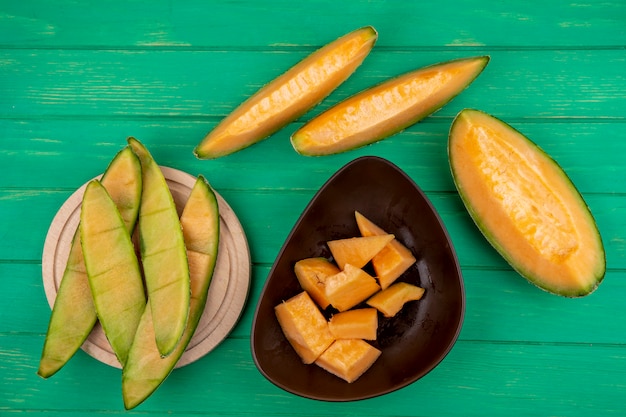 Vista superior de cáscaras de melón sobre una tabla de cocina de madera con rodajas de melón en un tazón marrón