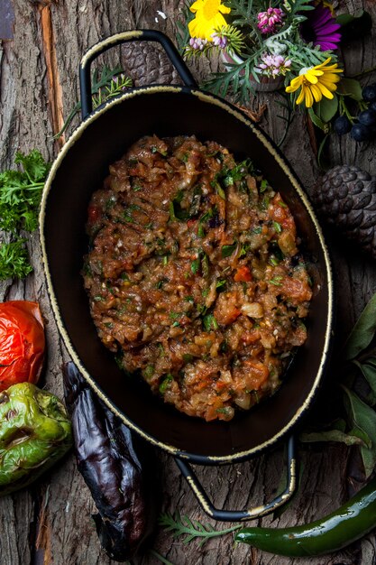 Vista superior de caviar de berenjena con tomate, perejil, albahaca en una sartén vertical