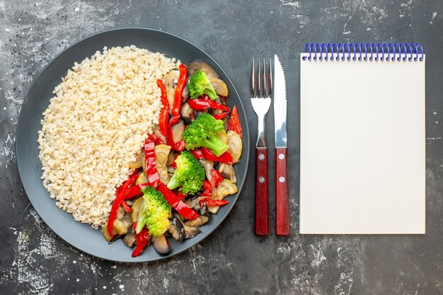 Vista superior de cebada perlada con sabrosas verduras cocidas en la mesa gris