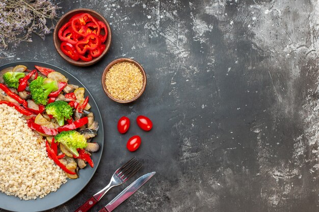 Vista superior de cebada perlada con sabrosas verduras cocidas en la mesa gris