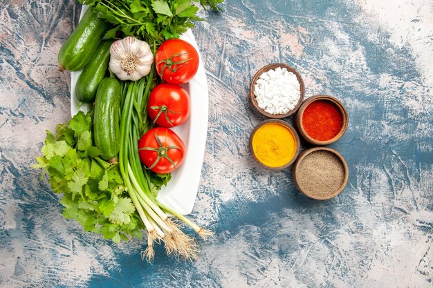 Vista superior de cebolla verde fresca con verduras y condimentos sobre fondo azul claro