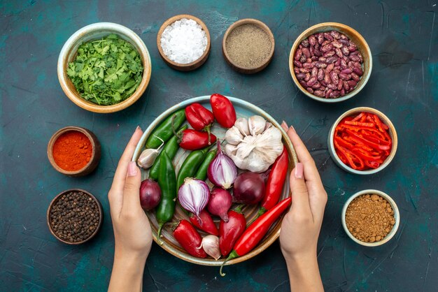 Vista superior de cebollas y ajos con verduras y condimentos en los ingredientes de ensalada de alimentos vegetales de mesa azul oscuro