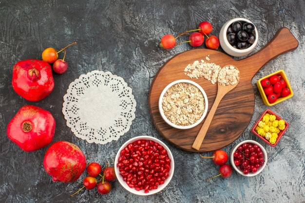 Vista superior de cerca bayas tapete de encaje granadas cerezas cuchara de avena bayas dulces amarillos