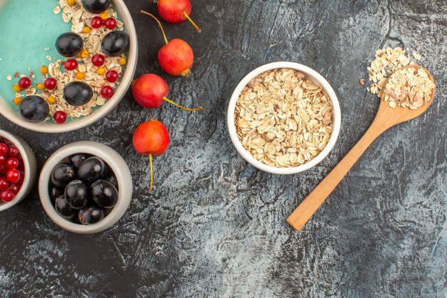 Vista superior de cerca bayas tazón de avena cuchara de madera grosellas rojas uvas negras bayas coloridas