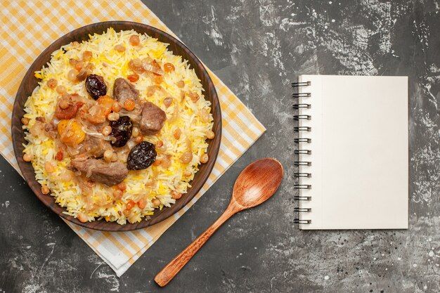 Vista superior de cerca una cuchara de pilaf un apetitoso pilaf en el cuaderno de mantel a cuadros