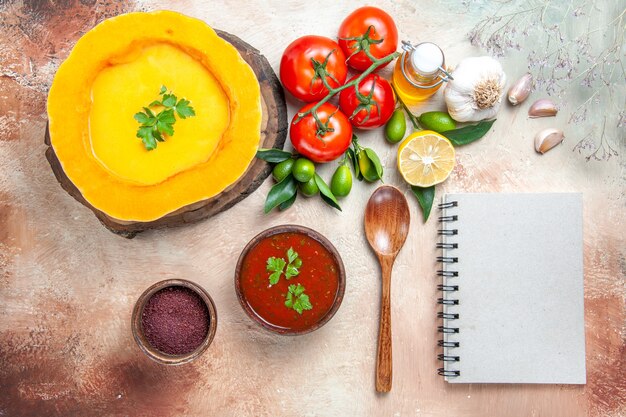 Vista superior de cerca cuchara de sopa tomates ajo aceite de limón sopa de calabaza salsa cuaderno blanco