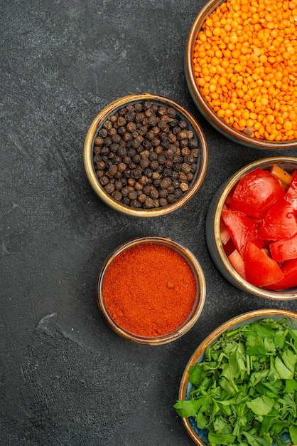 Vista superior de cerca cuencos de lentejas de lentejas hierbas tomates pimienta negra especias