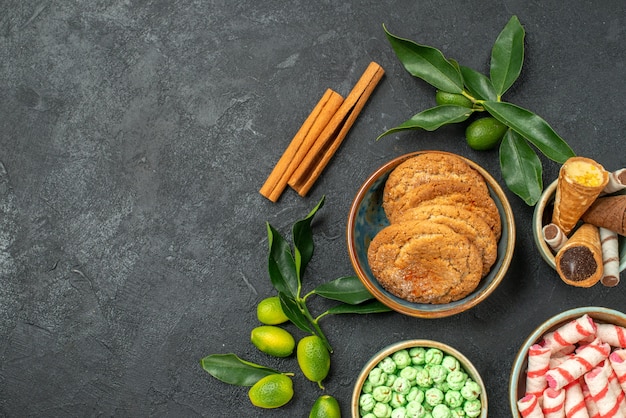 Vista superior de cerca dulces dulces palitos de canela frutas cítricas con hojas waffles cookies