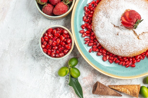 Vista superior de cerca dulces un pastel con granada tazones de frutas cítricas de granada de fresas