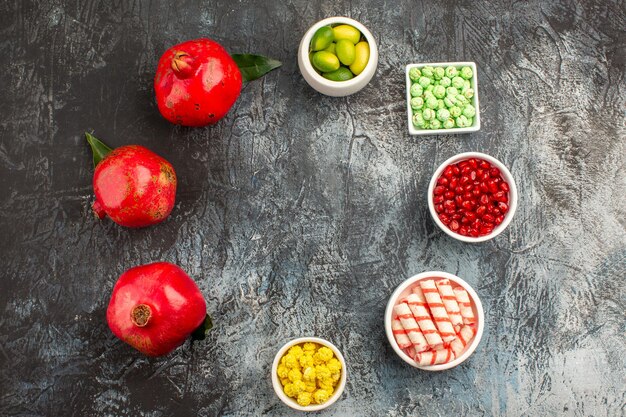 Vista superior de cerca dulces tazones de frutas cítricas de granada de caramelos de colores