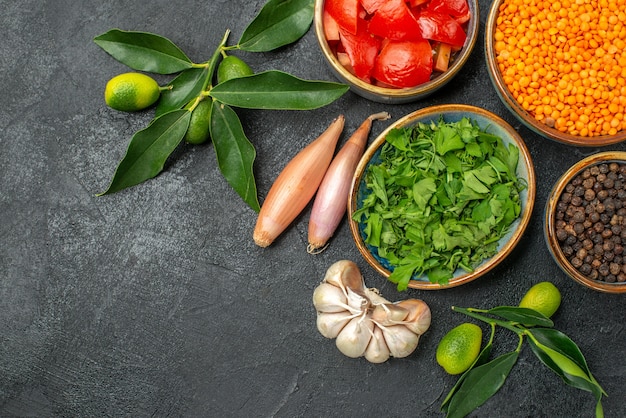 Vista superior de cerca especias cuencos de tomates lentejas pimienta negra hierbas cebolla ajo