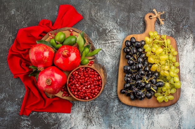 Foto gratuita vista superior de cerca frutas granadas sobre el mantel rojo y racimos de uvas en el tablero