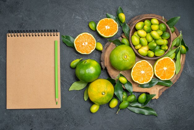 Vista superior de cerca frutas tablero de frutas cítricas cuaderno lápiz verde