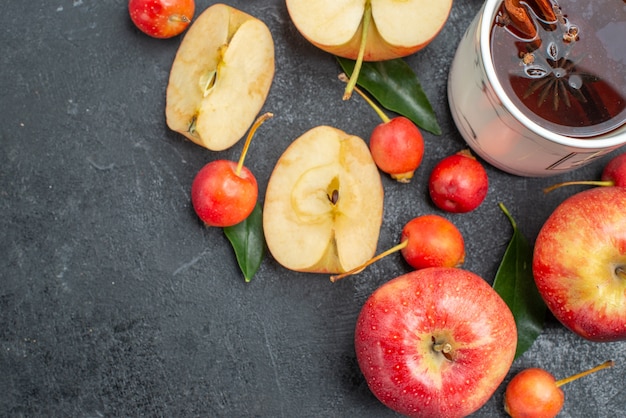 Vista superior de cerca frutas una taza de té manzanas cerezas con hojas