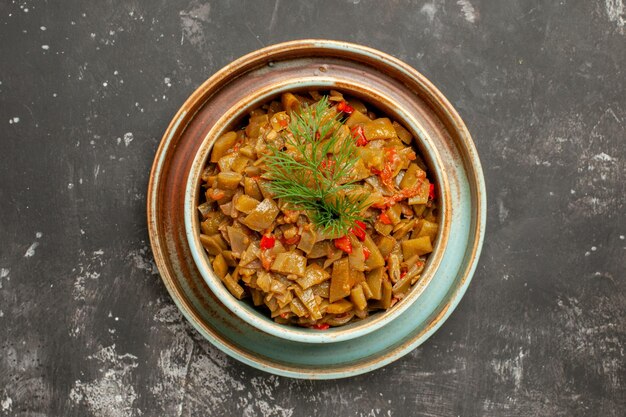 Vista superior de cerca judías verdes y tomates judías verdes con tomates en un recipiente sobre la mesa oscura