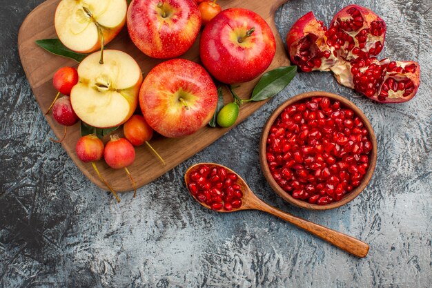 Vista superior de cerca manzanas Granada cuchara la tabla de cortar con cerezas manzanas