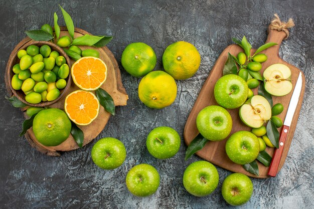 Vista superior de cerca manzanas manzanas verdes con hojas cuchillo en el tablero frutas cítricas