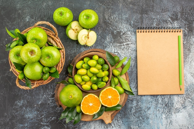 Vista superior de cerca manzanas el tablero con frutas cítricas cesta de manzanas lápiz de cuaderno